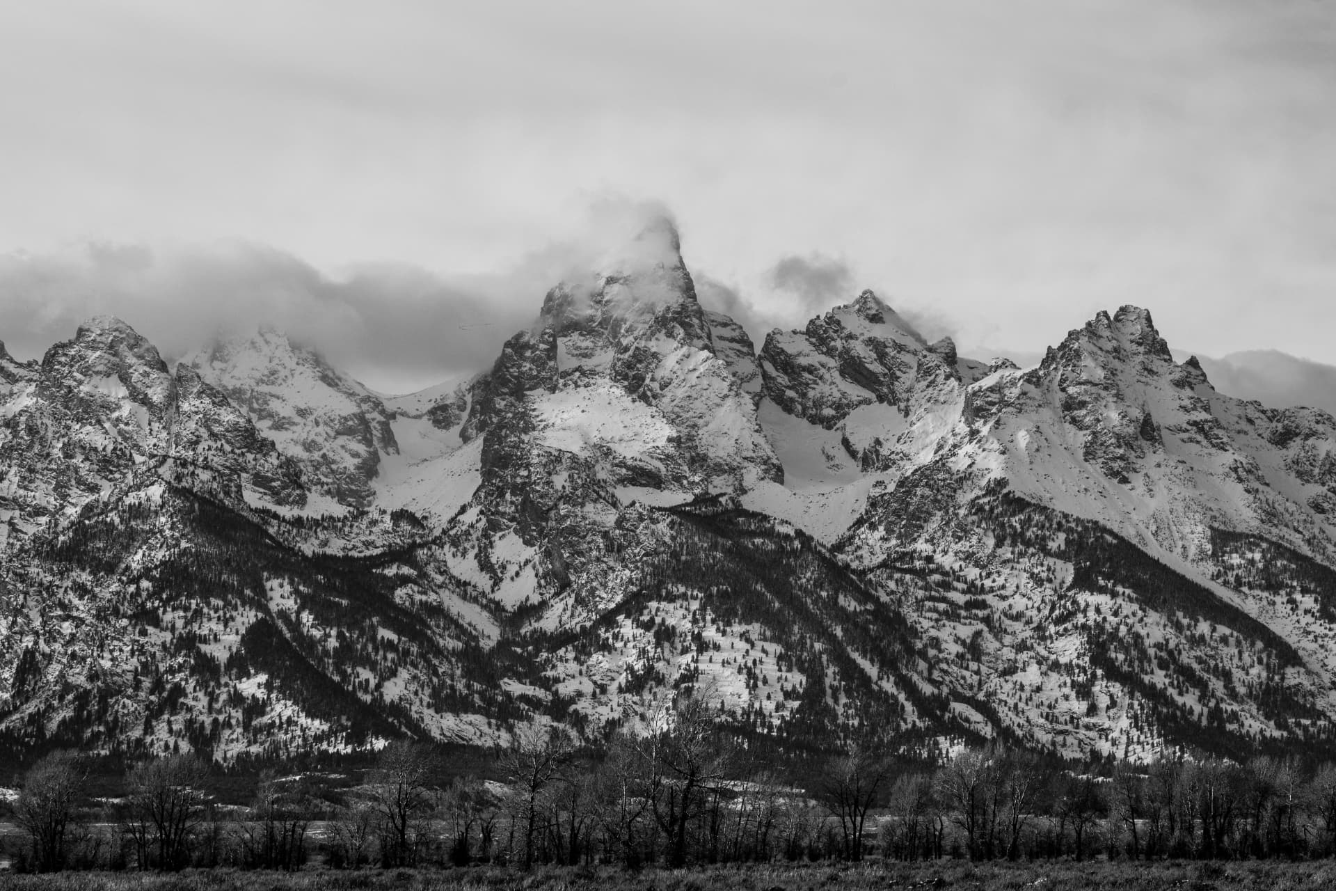 Snow-covered Teton mountain peaks under heavy clouds